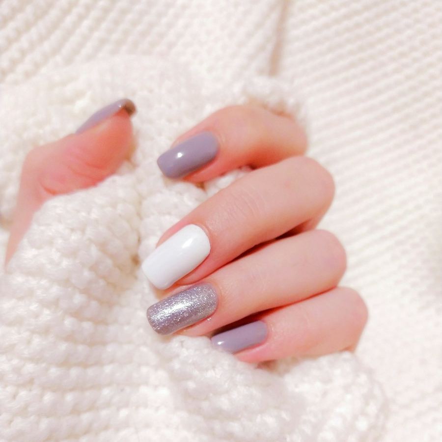 Mani con unghie curate e smalto chiaro su una coperta di lana